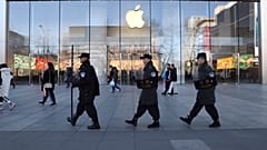 Çinli güvenlik görevlileri Pekin, Çin'deki bir Apple mağazasının önünden geçiyor.