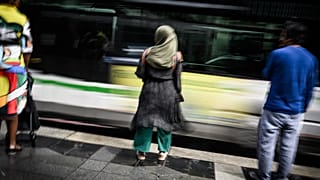 A young woman wears an Abaya as she stands on a street in Nantes