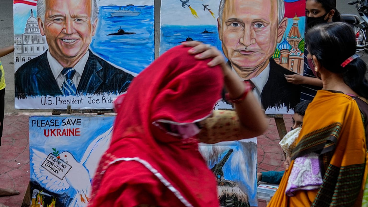 File - A woman adjusts her sari as she walks past art works by students calling for peace amid fears of a Russian offensive on Ukraine, on a pavement in Mumbai, India