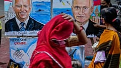 File - A woman adjusts her sari as she walks past art works by students calling for peace amid fears of a Russian offensive on Ukraine, on a pavement in Mumbai, India