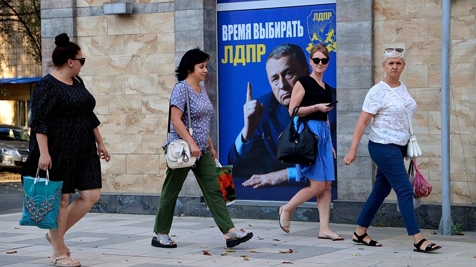 Women walk past a Russian Liberal Democratic Party poster with an image of former party leader Vladimir Zhirinovsky prior to local elections in Donetsk, eastern Ukraine.