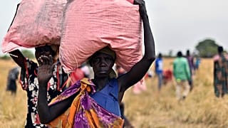 Locals in South Sudan collect the food drop of grain, delivered by the World Food Programme.