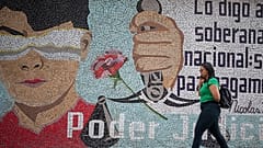 امرأة تمر أمام لوحة جدارية تصور رمز سيدة العدل في المحكمة في كاراكاس-25 أغسطس 2023.