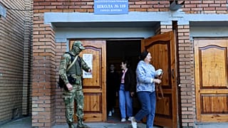 A serviceman guards an entrance of a polling station during a local elections in Donetsk, the capital of Russian-controlled Donetsk region, eastern Ukraine, on Sept. 10, 2023.