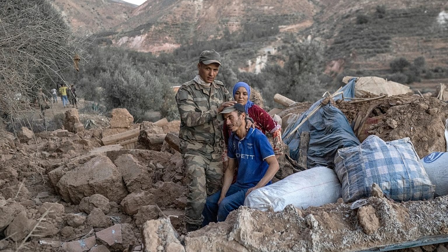 A Moroccan soldier comforts a man sitting on rubble on September 11, 2023.