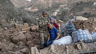 A Moroccan soldier comforts a man sitting on rubble on September 11, 2023.
