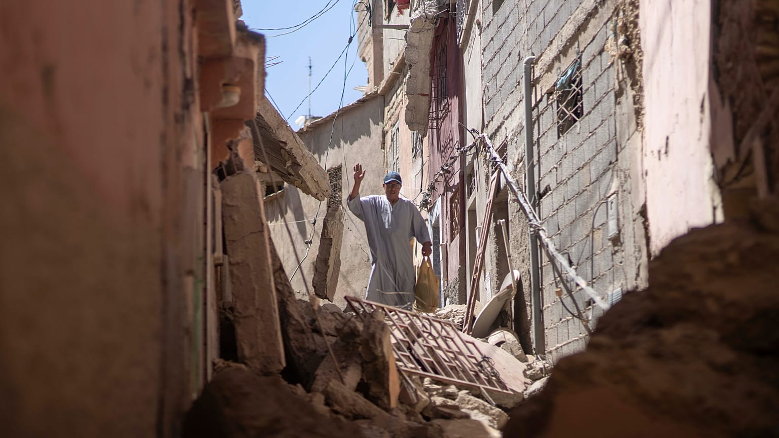 Un hombre saluda a sus amigos mientras camina entre los escombros causados por el terremoto, en Amizmiz, cerca de Marrakech, Marruecos, el domingo 10 de septiembre de 2023.