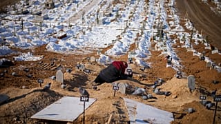 A woman cries over the graves of her son and daughter, killed during the earthquake of February 2023, at Sehir cemetery in Malatya, Sunday, Feb. 12, 2023