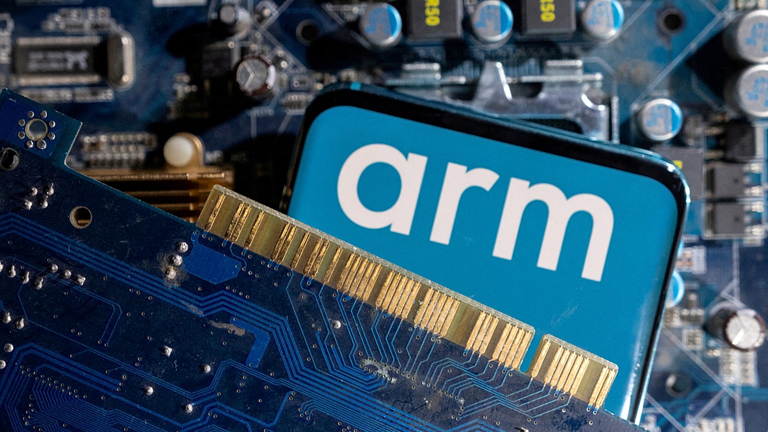 A smartphone with a displayed Arm Ltd logo is placed on a computer motherboard