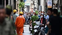 سكان يقفون خلف حاجز بالقرب من موقع حريق كبير في مبنى سكني في هانوي