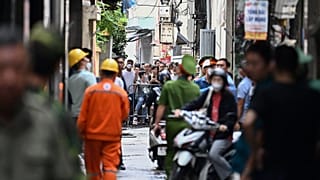 سكان يقفون خلف حاجز بالقرب من موقع حريق كبير في مبنى سكني في هانوي