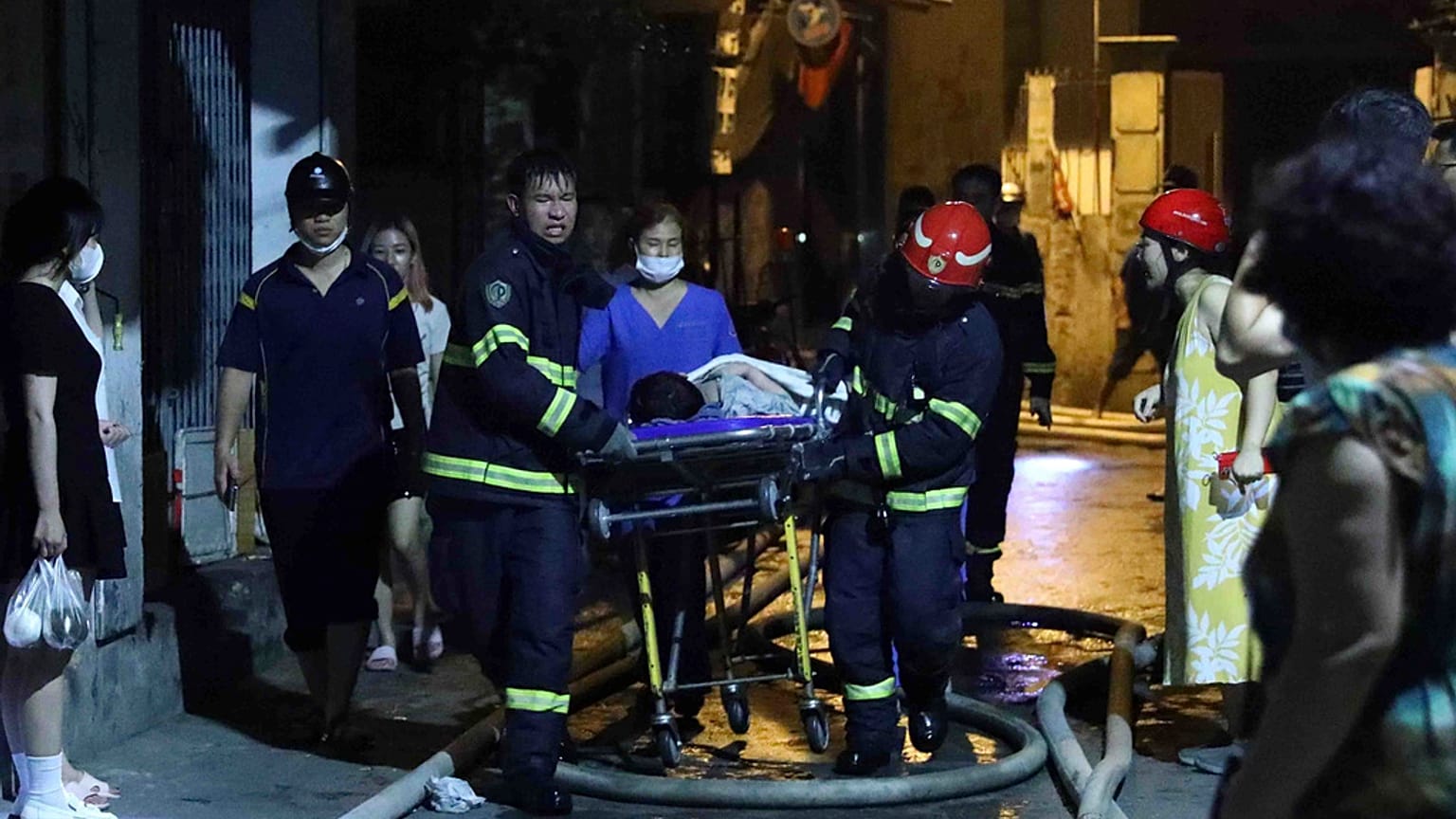 Διασώστες μεταφέρουν τραυματίες σε φορείο μετά την μεγάλη πυρκαγιά σε πολυκατοικία στο Ανόι του Βιετνάμ