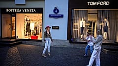 Transeuntes posam à porta de boutiques de luxo no centro de Moscovo, apesar das sanções e da guerra. 21 de agosto de 2023.