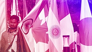 A worker carries Indian flag to place it with those of other participating countries at the opening session of the G20 foreign ministers meeting, in New Delhi, March 2023