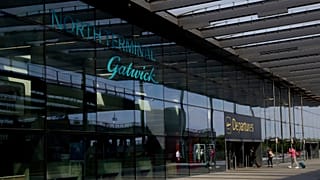 Passengers walk into the Departures entrance at the North Terminal of Gatwick Airport. 
