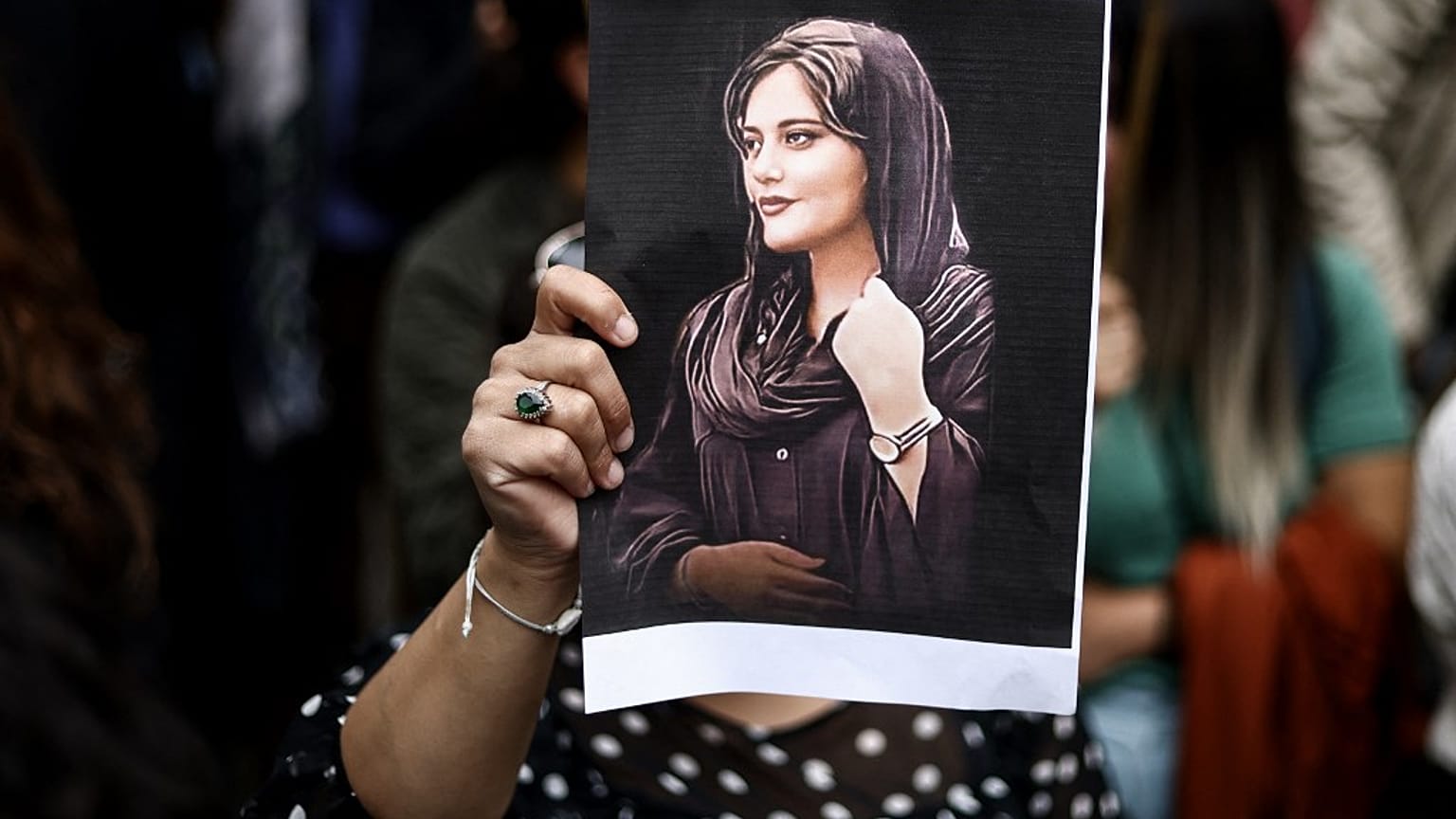 Una donna mostra la foto di Mahsa Amini 