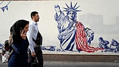 Passanten in Teheran laufen an eine einem antiamerikanischen Wandgemälde vorbei