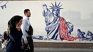 Passanten in Teheran laufen an eine einem antiamerikanischen Wandgemälde vorbei