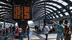 Viaggiatori controllano sui tabelloni ferroviari le variazioni degli orari alla stazione centrale di Milano  
