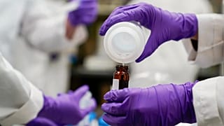 A water researcher pours a sample into a glass container for experimentation as part of drinking water and PFAS research at the US Environmental Protection Agency.