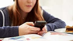 Teenager telefoniert in einer Lernpause mit ihrem Handy.
