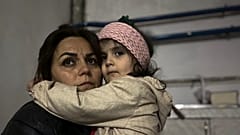 Menina abraça familiar sentada num abrigo durante um bombardeamento em Stepanakert, em Nagorno-Karabakh.