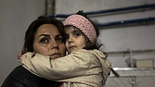 Menina abraça familiar sentada num abrigo durante um bombardeamento em Stepanakert, em Nagorno-Karabakh.