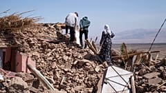 سكان يمشون فوق ركام بيتهم الذي دمره الزلزال في قرية تافغغت الجبلية قرب مراكش