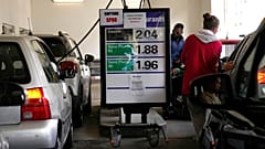 People fill up their tank at a gas station where placards read "No unleaded oil" and "Filling up jerry cans is forbidden", Wednesday, Oct. 12, 2022 in Cachan, outside Paris.