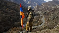 FILE - In this Wednesday, Nov. 25, 2020 file photo, an ethnic Armenian soldier stands guard next to Nagorno-Karabakh's flag atop of the hill.