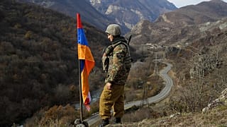 FILE - In this Wednesday, Nov. 25, 2020 file photo, an ethnic Armenian soldier stands guard next to Nagorno-Karabakh's flag atop of the hill.