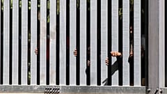 Members of a group of some 30 migrants seeking asylum are seen in Bialowieza, Poland, on May 28, 2023 across a wall that Poland has built on its border with Belarus