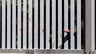 Members of a group of some 30 migrants seeking asylum are seen in Bialowieza, Poland, on May 28, 2023 across a wall that Poland has built on its border with Belarus