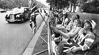 FILE - Potential spectators get into their early positions along the Mall, the wide road running from Buckingham Palace in London, July 22, 1986.