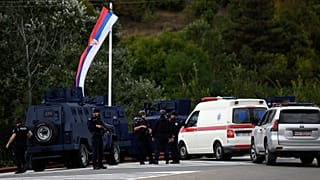 Kosovo's police officers stand guard at the entrance of the village of Banjska on Sunday, after one policeman was killed and another wounded i