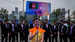 A volunteer holds up country's sign for Afghan men's only team during a welcoming ceremony at the 19th Asian Games in Hangzhou, China on Wednesday