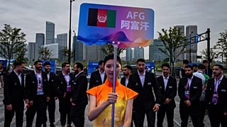 A volunteer holds up country's sign for Afghan men's only team during a welcoming ceremony at the 19th Asian Games in Hangzhou, China on Wednesday