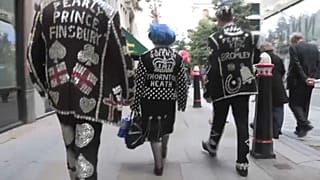 Tracking shot pearly kings and queens marching in Guildhall Yard in London.