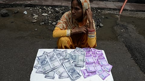 An Indian woman sells wallets printed with the images of Indian currency 500 and 2000 rupee notes on a street in Hyderabad on June 8, 2017.