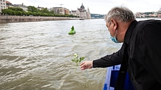 A man throws a flower into River Danube from a ship during an ecumenical commemoration marking the second anniversary of a fatal boat accident on the River Danube, in Budapest