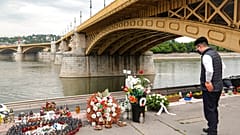 Un hombre junto a velas y flores colocadas sobre el río Danubio durante una ceremonia en memoria de las víctimas, un año después del accidente del barco.