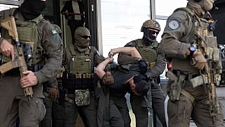Membros da Unidade de Intervenção Especial da polícia do Kosovo escoltam um dos atiradores