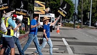 Screenwriters Meagan Daine, right, and Craig Stiles join in support SAG-AFTRA picketers outside the gates of Warner Bros. studios in California, Tuesday, Sep. 26, 2023