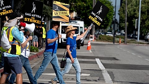 Screenwriters Meagan Daine, right, and Craig Stiles join in support SAG-AFTRA picketers outside the gates of Warner Bros. studios in California, Tuesday, Sep. 26, 2023