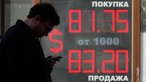FILE - A man stands next to an exchange office screen showing the currency exchange rates of U.S. Dollar to Russian Rubles in St. Petersburg, Russia, Friday, April 7, 2023. 