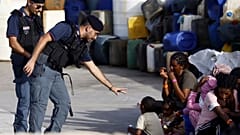 A police officer plays with a migrant child blowing soap bubbles in the port of the Sicilian island of Lampedusa, southern Italy, Monday, Sept. 18, 2023.