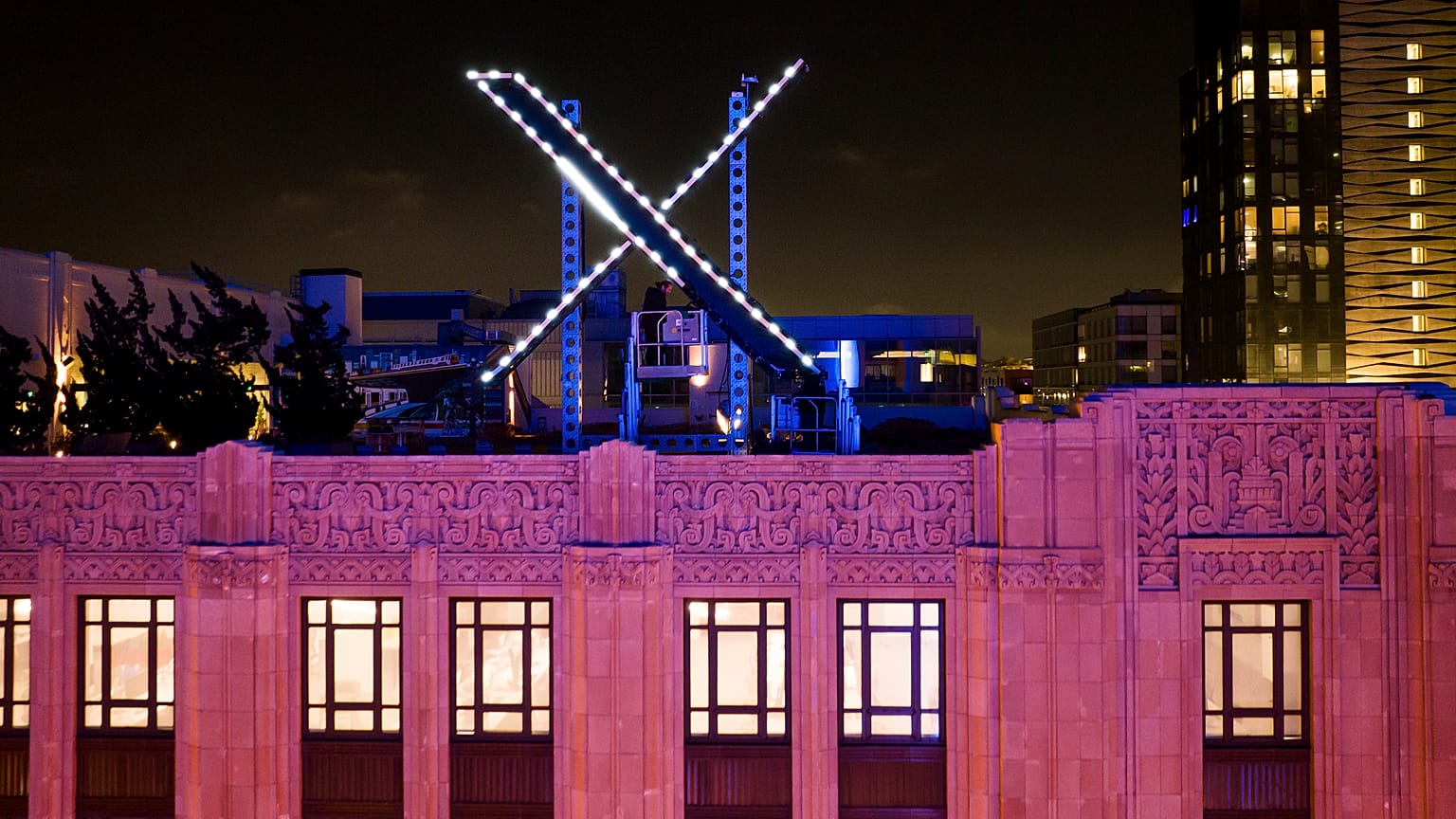 Workers install lighting on an "X" sign atop the company headquarters, formerly known as Twitter, in downtown San Francisco