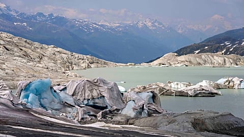 Chunks of ice covered by sheets float in a lake at the Rhone Glacier near Goms, Switzerland, 16 June 2023. 