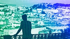 A young man takes looks from a viewpoint overlooking downtown Lisbon, August 2022