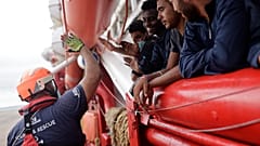 Un voluntario de SOS Mediterranee choca los cinco con unos inmigrantes que se acercan a las costas italianas, el 4 de septiembre de 2022 frente a Taranto, en el sur de Italia.